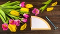 Spring bouquet of yellow and pink tulips, flower petals notebook with place for text, pen Royalty Free Stock Photo