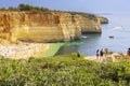 Tourists standing in the cliff to view the beautiful beach of Benagil in Algarve. Algarve, Portugal, Europe.