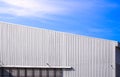 Aluminum corrugated industrial warehouse building and gable roof with sunlight reflection on metal wall surface against blue sky Royalty Free Stock Photo