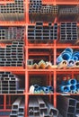 many carbon steel rectangular and square tubes with blue PVC water pipes on storage shelf of building supply store Royalty Free Stock Photo