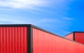 Red and black aluminium roofs of two metal industrial warehouse buildings against blue sky background in perspective side view Royalty Free Stock Photo