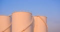 Orange sunlight on surface of 3 storage fuel tanks in petrochemical refinery area against blue evening sky background Royalty Free Stock Photo