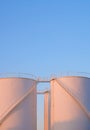 Orange sunlight on surface of 3 white storage fuel tanks in petrochemical refinery area against blue evening sky background Royalty Free Stock Photo