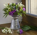 A bright bouquet of spring wildflowers with lilies of the valley in a vintage jug on a window in sunlight Royalty Free Stock Photo