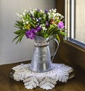 A bright bouquet of spring wildflowers with lilies of the valley in a vintage jug on a window in sunlight. Royalty Free Stock Photo