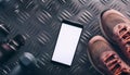 A smartphone with white screen and sneekers on metal background Royalty Free Stock Photo