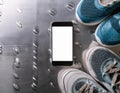 A smartphone with white screen and sneekers on metal background Royalty Free Stock Photo