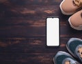 A smartphone with white screen and sneekers on wooden background Royalty Free Stock Photo