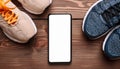 A smartphone with white screen and sneekers on wooden background Royalty Free Stock Photo