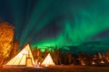 Northern lights dancing over the light up Tipi or Tepees at Aurora Village in Yellowknife, Northwest Territories, Canada. Royalty Free Stock Photo