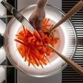 Dicing carrots in a glass bowl, top view. Carrots with knife and wooden spoon Royalty Free Stock Photo
