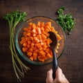 Dicing carrots in a glass bowl, top view. Carrots with knife and wooden spoon Royalty Free Stock Photo