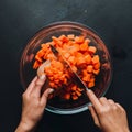 Dicing carrots in a glass bowl, top view. Carrots with knife and wooden spoon Royalty Free Stock Photo
