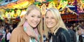 Two young blonde women as best friends have fun at a funfair at night Royalty Free Stock Photo