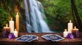 Deep green forest waterfall with a table in the foreground with gold tarot cards, lit candles, and amethyst crystals Royalty Free Stock Photo
