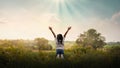 Praising the lord concept. Back view of a young girl with her arms raised to the sky in thankfulness and prayer Royalty Free Stock Photo