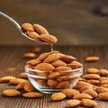 Almonds Almond Nuts Food. Raw almonds pouring out of a glass bowl onto a wood surface. Royalty Free Stock Photo