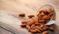 Almonds Almond Nuts Food. Raw almonds pouring out of a glass bowl onto a wood surface. Royalty Free Stock Photo