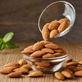 Almonds Almond Nuts Food. Raw almonds pouring out of a glass bowl onto a wood surface. Royalty Free Stock Photo