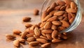 Almonds Almond Nuts Food. Raw almonds pouring out of a glass bowl onto a wood surface. Royalty Free Stock Photo