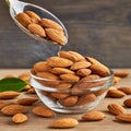 Almonds Almond Nuts Food. Raw almonds pouring out of a glass bowl onto a wood surface. Royalty Free Stock Photo