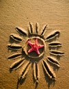 A sun with rays is drawn on the sand, and a sea red star was placed. Sun, rays, travel, starfish. Royalty Free Stock Photo
