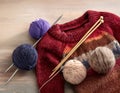 Knitted sweaters with knitting needles and wool in basket Royalty Free Stock Photo