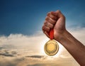 Success. Male hand rise up a gold medal against the dramatic sky with copy space Royalty Free Stock Photo