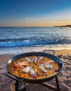 Spanish paella on the beach. A typical spanish paella with seafood in a paellera, the paella pan, on the beach Royalty Free Stock Photo