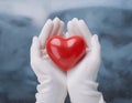 Woman hands are holding a beautiful glossy red heart in a snow winter background Royalty Free Stock Photo