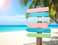 Pastel colored wooden direction signs, beach and palm tree background Royalty Free Stock Photo
