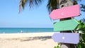 Pastel colored wooden direction signs, beach and palm tree background Royalty Free Stock Photo