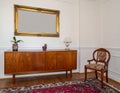 Vintage living room interior with a patterned rug, cupboard, golden frame on the wall Royalty Free Stock Photo