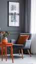 Grey armchair at orange table in dark retro living room interior with drapes Royalty Free Stock Photo