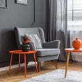 Grey armchair at orange table in dark retro living room interior with drapes Royalty Free Stock Photo