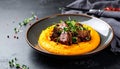 Tender braised beef cheeks served atop smooth pumpkin puree, garnished with microgree Royalty Free Stock Photo