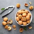 Fresh walnuts in bowl and nutcracker on gray table, flat lay. Royalty Free Stock Photo