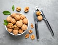 Fresh walnuts in bowl and nutcracker on gray table, flat lay. Royalty Free Stock Photo