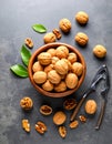 Fresh walnuts in bowl and nutcracker on gray table, flat lay. Royalty Free Stock Photo