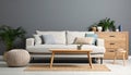 Soft sofa, coffee table, pouf, houseplants and chest of drawers near grey wall in live room Royalty Free Stock Photo