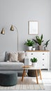 Soft sofa, coffee table, pouf, houseplants and chest of drawers near grey wall in live room Royalty Free Stock Photo
