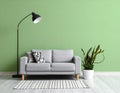 Stylish sofa with pillow, houseplant and lamp near green wall indoors Royalty Free Stock Photo