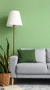 Stylish sofa with pillow, houseplant and lamp near green wall indoors Royalty Free Stock Photo