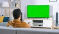 The man who watches modern TV with a green screen at home Royalty Free Stock Photo