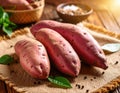 Three sweet potatoes with pinkish skin rest on a piece of burlap fabric Royalty Free Stock Photo