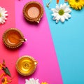 Diwali celebration. Diya lamps and beautiful flowers on colorful background, closed. Royalty Free Stock Photo