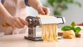 Woman preparing noodles with pasta maker machine at table indoors, closeup Royalty Free Stock Photo