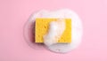 Yellow sponge with foam on pink background, top view. Royalty Free Stock Photo