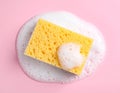 Yellow sponge with foam on pink background, top view. Royalty Free Stock Photo