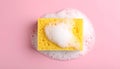 Yellow sponge with foam on pink background, top view. Royalty Free Stock Photo